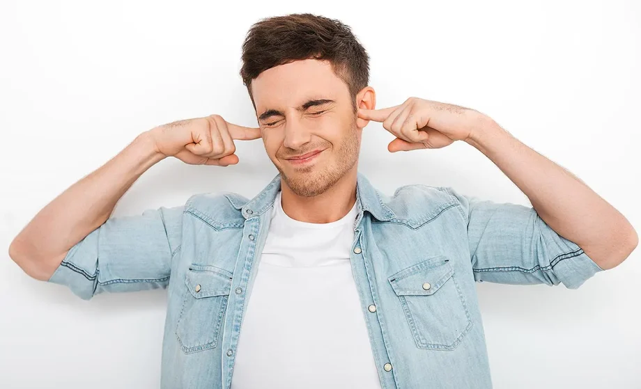 Isolation phonique nuisances sonores : un homme en chemise jean se bouchant les oreilles, visiblement gêné par le bruit